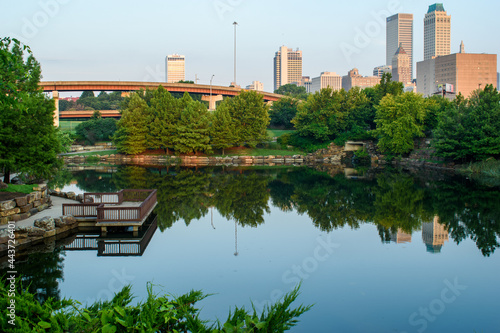 Morning photo of beautiful Centennial Park in Tulsa, OK with the downtown skyline in the background and reflecting on the pond. photo