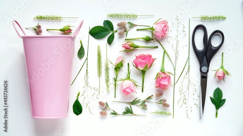 Fototapeta Naklejka Na Ścianę i Meble -  Floristic composition flat lay.Work of the florist,drawing up a flower arrangement,on a white table pink bucket,scissors, roses,flowers and herbs,top view.Floral banner.Pastel colors.
