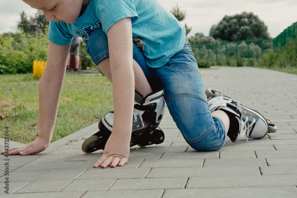 A boy tries to get up from the ground after falling with the roller skates. a boy riding a bike or roller, fell and injured his leg