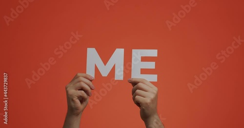 Hands showing word me. 4k video of arms with pronoun made of carved paper. English language learning