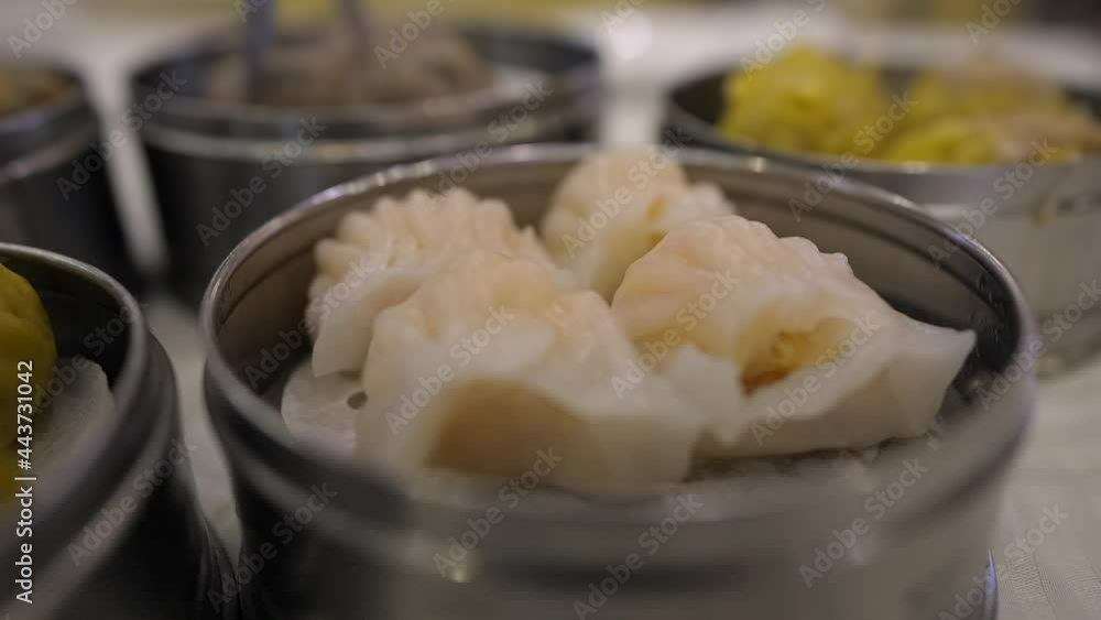 This close up video shows a delicious dish of shrimp dumpling ha gow with a dim sum feast in the background. This close up video shows a delicious dish of shrimp dumpling ha gow with a dim sum feast in the background.