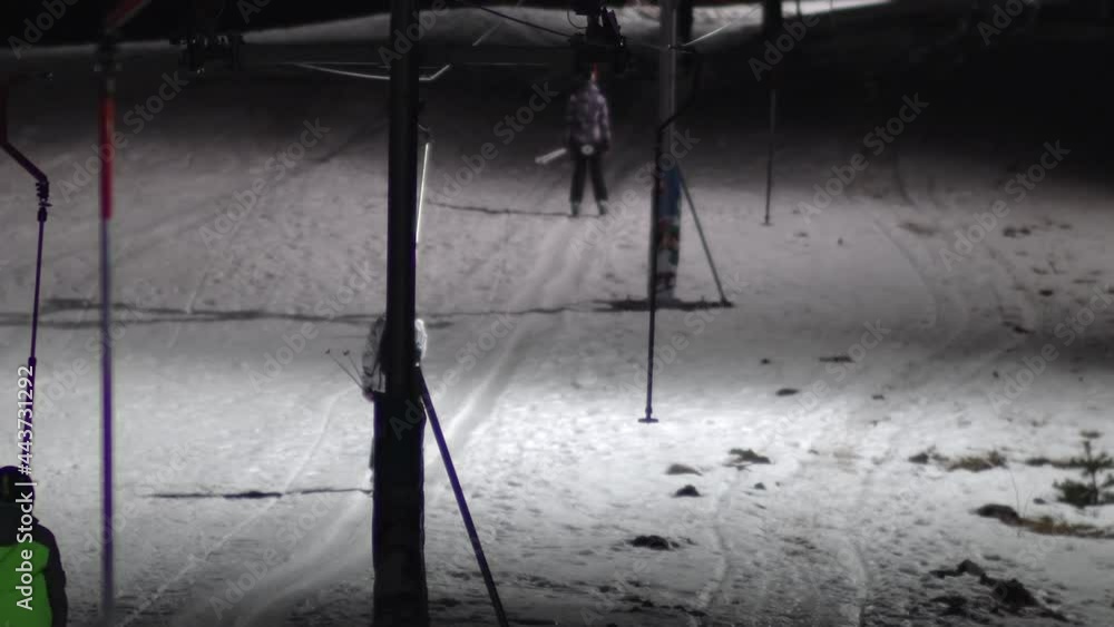 Night scene of a ski resort and people riding a drag lift (button ski