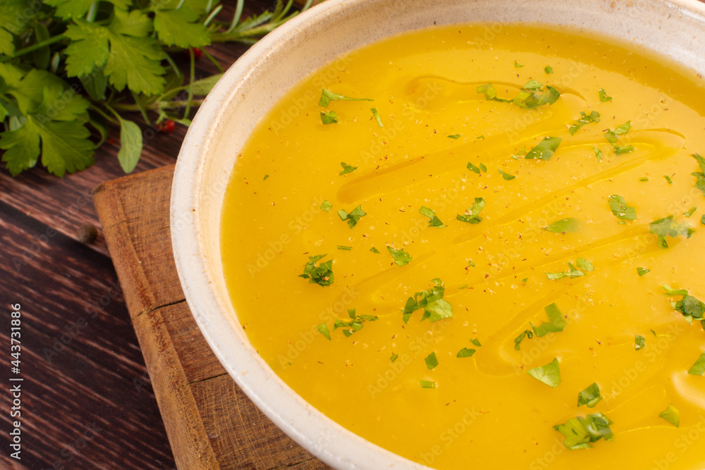 Hot cassava cream broth in a white bowl, on a wooden table (Brazilian caldo de mandioquinha)