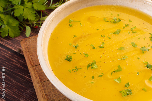 Hot cassava cream broth in a white bowl, on a wooden table (Brazilian caldo de mandioquinha) photo