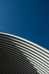 contemporary white grey metal curve architecture on blue sky background