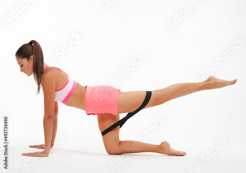 Resistance band fitness. Young woman doing leg workout donkey kick floor exercises with strap elastic.