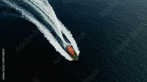 Aerial Drone Cinematic - chasing and circulating bright orange coast guard boat in the ocean right outside of the coast of Helsingborg Sweden and Helsingor Denmark in Oresund photo