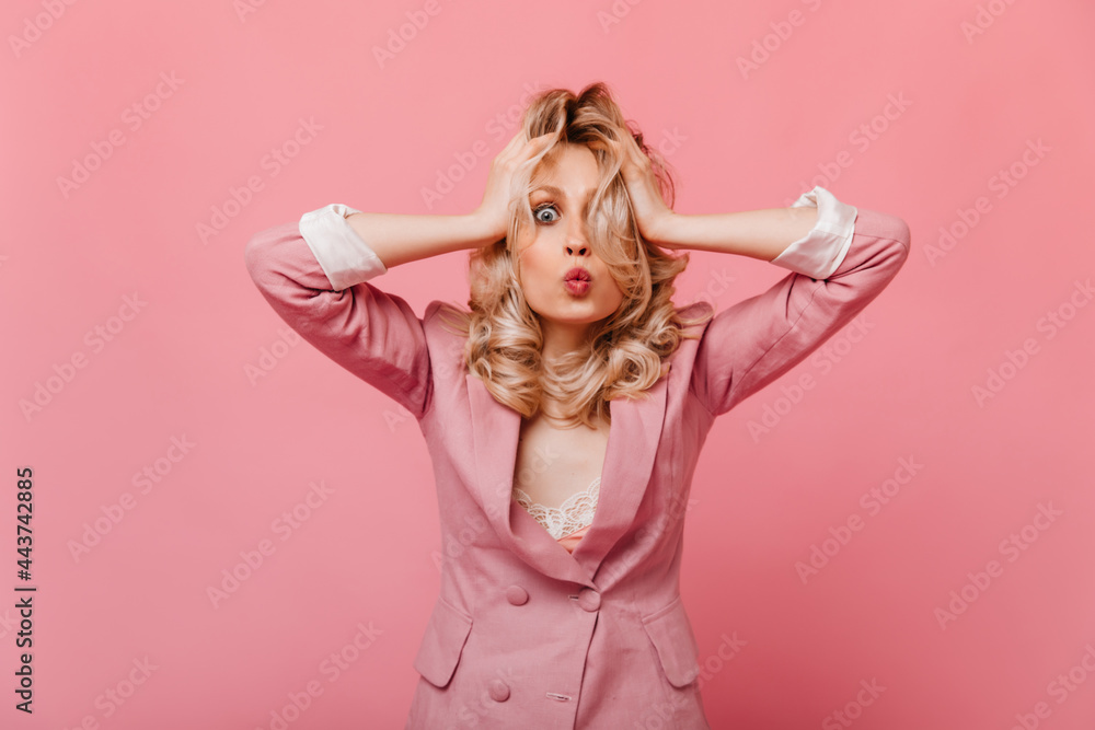 Model in pink jacket with rolled up white sleeves and sweet smile looking at camera with surprised facial expression Model in pink jacket with rolled up white sleeves and sweet smile looking at camera with surprised facial expression