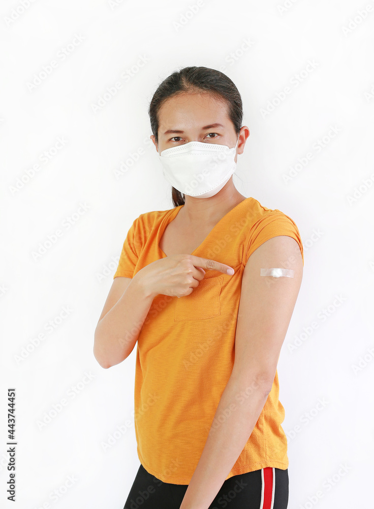Woman with protective mask pointing at arm with adhesive plaster, cotton from vaccinated. Asian female with plaster on the shoulder from the injection. Vaccination and Treatment concept Woman with protective mask pointing at arm with adhesive plaster, cotton from vaccinated. Asian female with plaster on the shoulder from the injection. Vaccination and Treatment concept