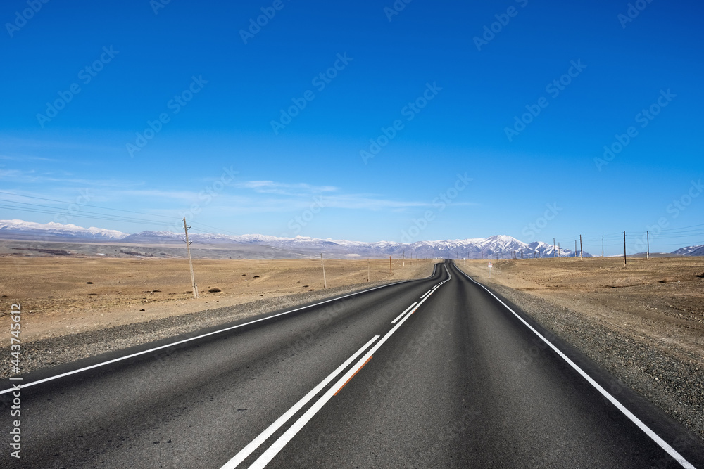 Fototapeta premium Beautiful view of Chuya Highway in Chuya Steppe, empty road and blue sky in Altai Republic