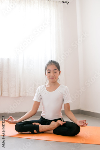 Niña mexicana practicando yoga sobre un tapete naranja a contraluz