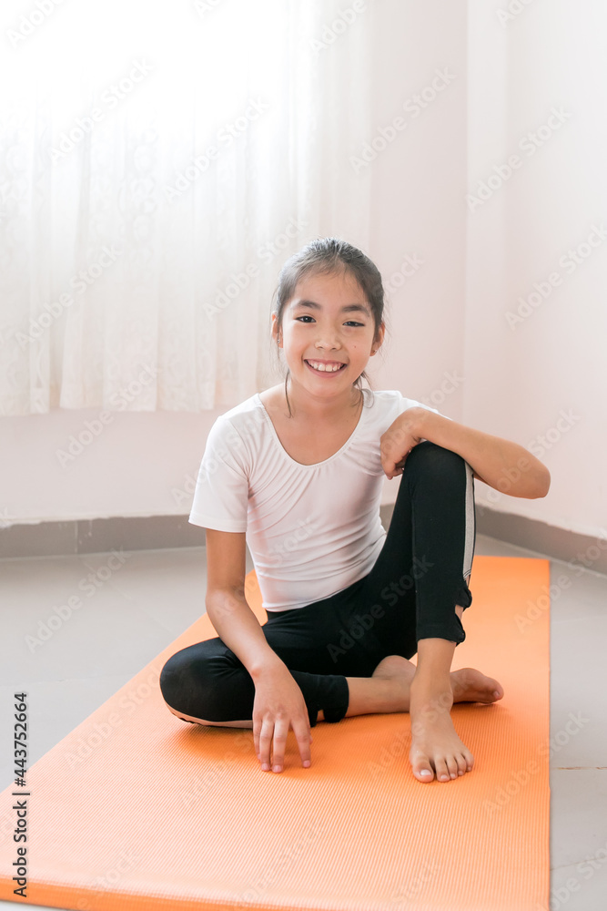 Niña mexicana practicando yoga sobre un tapete naranja a contraluz Niña mexicana practicando yoga sobre un tapete naranja a contraluz