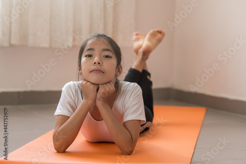 Niña mexicana practicando yoga sobre un tapete naranja a contraluz