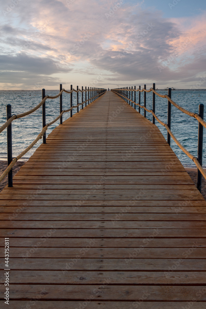 Wooden pier extending into the sea at sunrise