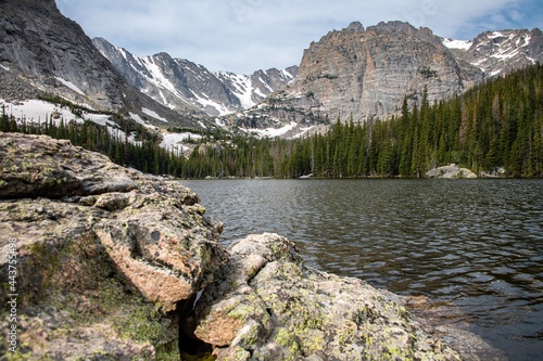 View of Loch Lake in Rocky Mountain National Park in Colorado. A mountain face can be seen as well as a large blue lake and blue skies with clouds and rocks. photo