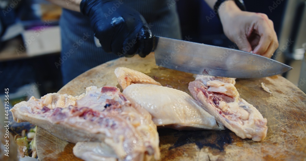 chef using knife chopping cutting fresh raw chicken on wooden cutting board at the kitchen, preparing meat for cooking food