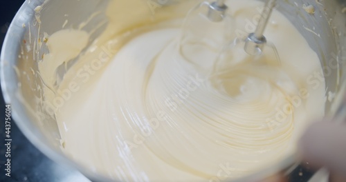 close up automatic flour mixing machine mixing delicious cream to make cake. ingredient of cake is egg, butter and sugar in the bowl, making bakery 