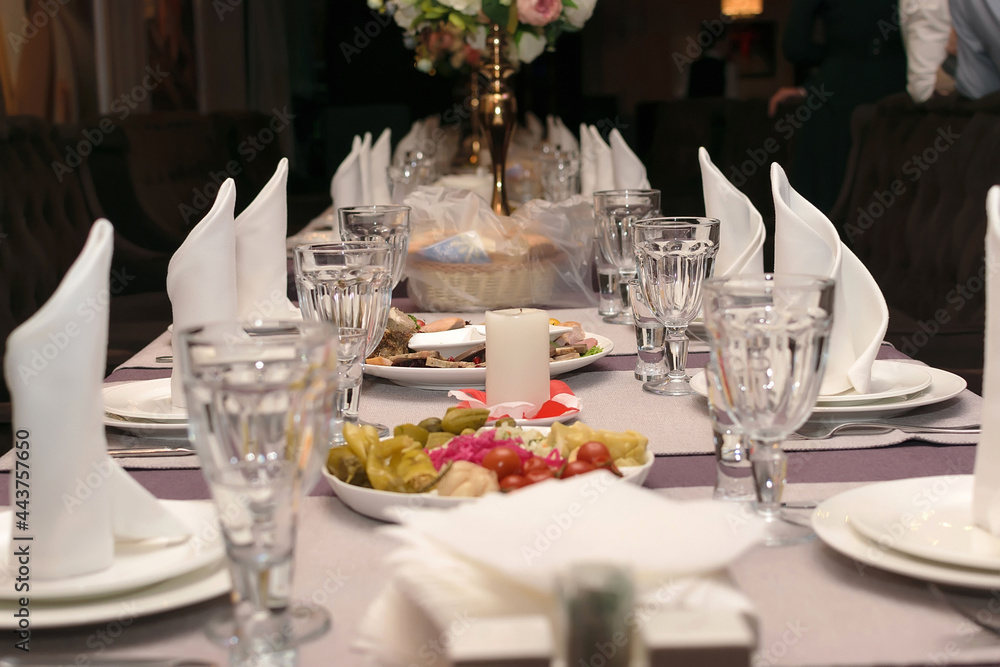 Table set in a restaurant with a candle in the middle of the table with snacks, empty glasses of wine, clean plates and standing white napkins