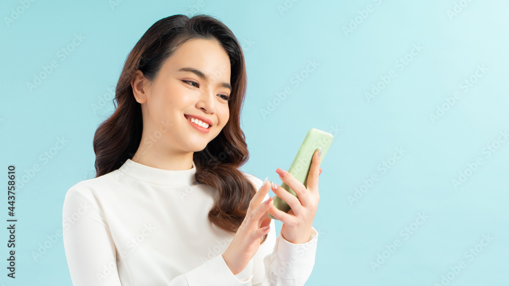 attractive asian woman using smart phone isolated on blue background attractive asian woman using smart phone isolated on blue background