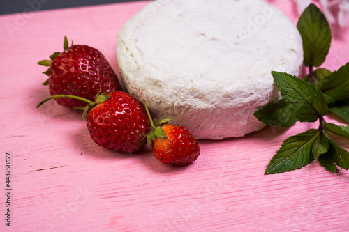 Camembert with strawberries with mint on a pink wooden board on a grey background 
