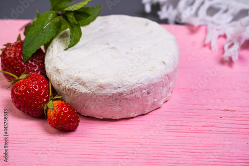 Camembert with strawberries with mint on a pink wooden board on a grey background 