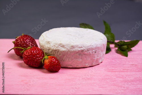 Camembert with strawberries with mint on a pink wooden board on a grey background 