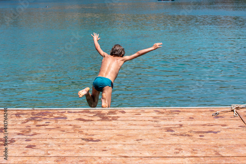 happy boy jumping from a bridge into the sea, vacation horizontal.