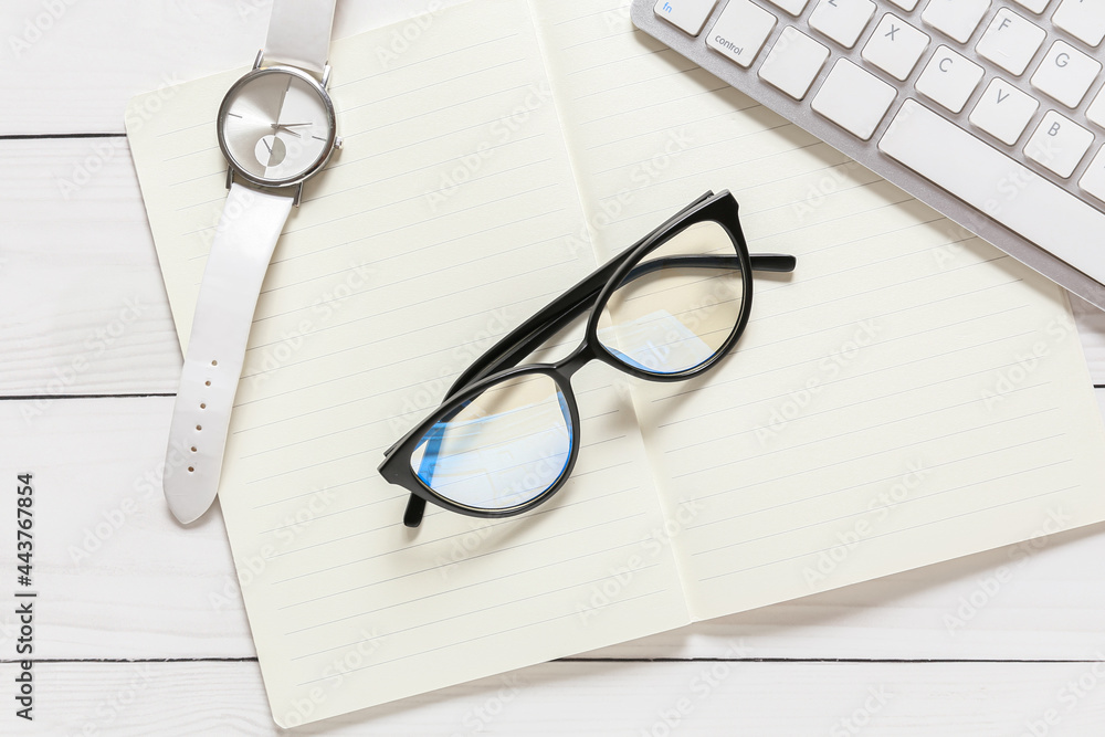 Composition with eyeglasses and notebook on white wooden background Composition with eyeglasses and notebook on white wooden background