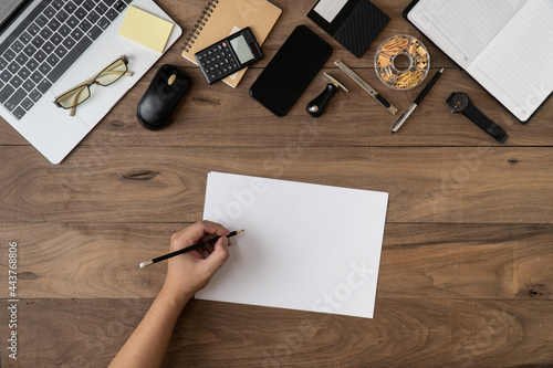 left hand writing message information on empty notebook list template with office accessories on table flat lay.Working on office desk flat lay.To do list on document concept.