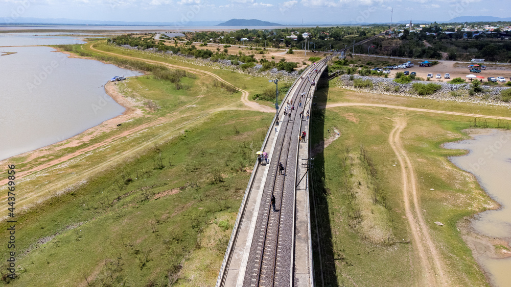 Aerial Unseen view of railroad tracks of floating Train bridge with white car in Khok Salung, Pa Sak Jolasid dam Lopburi amazing Thailand, Known as a floating train route. Aerial Unseen view of railroad tracks of floating Train bridge with white car in Khok Salung, Pa Sak Jolasid dam Lopburi amazing Thailand, Known as a floating train route.