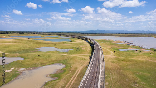 Aerial Unseen view of railroad tracks of floating Train bridge with white car in Khok Salung, Pa Sak Jolasid dam Lopburi amazing Thailand, Known as a floating train route.