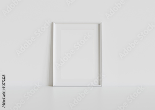 Fototapeta Naklejka Na Ścianę i Meble -  White frame leaning on white floor in interior mockup. Template of a picture framed on a wall 3D rendering