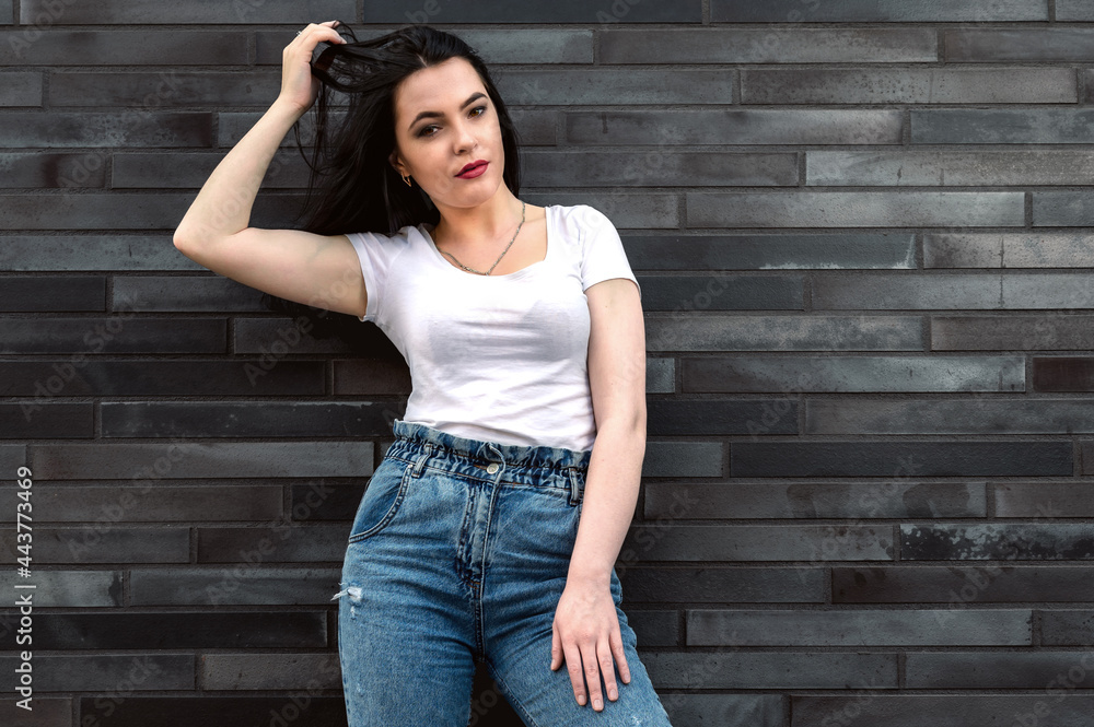 Portrait of a young woman outdoors on the background of a building. Young girl near the building Portrait of a young woman outdoors on the background of a building. Young girl near the building