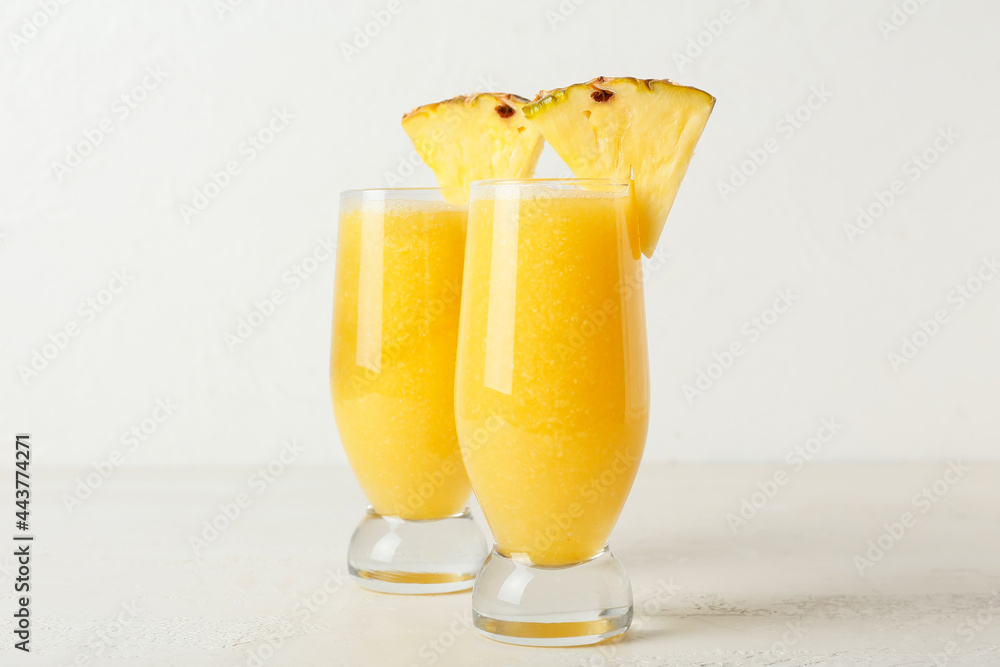 Glasses of tasty pineapple smoothie on light background Glasses of tasty pineapple smoothie on light background