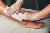 Close up photo of a caucasian spa worker having leg epilation procedures with a lying on the couch client