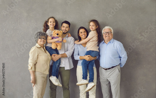 Studio photo shoot group portrait of cheerful big extended multi generational family against grey background.Happy smiling mom, dad, grandma, grandpa and two little kids all together looking at camera photo