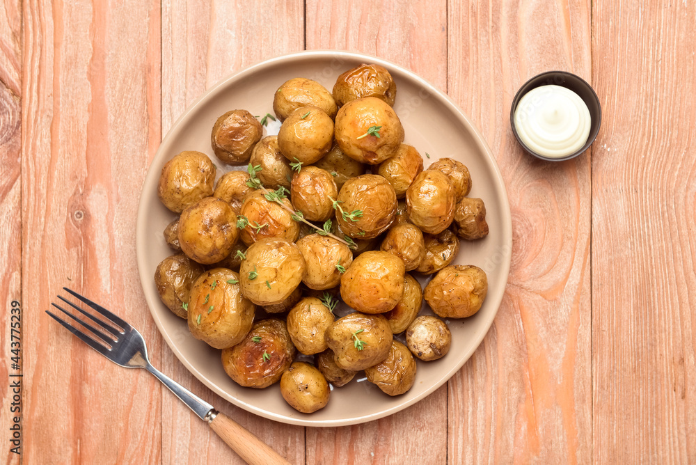 Plate with tasty baked potato on wooden background