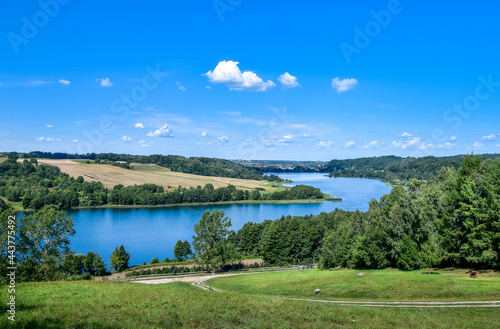 Beautifil view on Kaszuby lake district. Lake surrounded by trees and fields on a sunny, summer day.