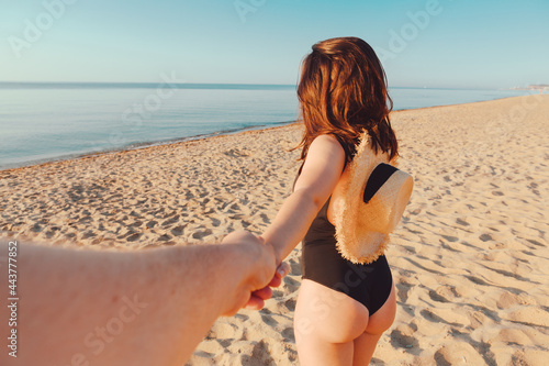 woman holding hand man. follow me concept. walking by sea beach on sunset
