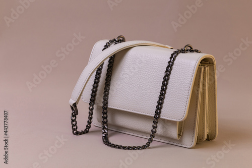 Beige leather women's handbag on fabric background. Fashion and shopping concept