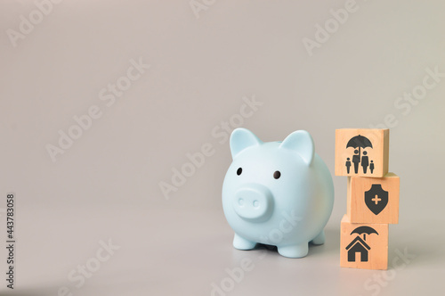 Piggy bank and wooden block with insurance symbols.