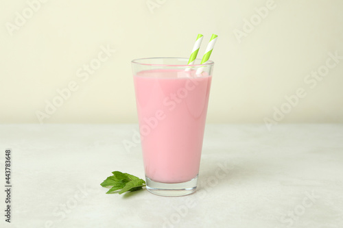 Glass of strawberry milkshake on white textured table