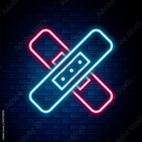 Glowing neon line Crossed bandage plaster icon isolated on brick wall background. Medical plaster, adhesive bandage, flexible fabric bandage. Colorful outline concept. Vector