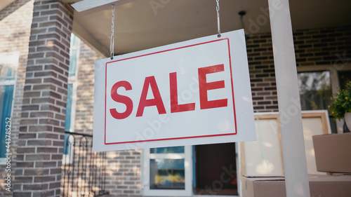 sticky label with sale lettering on board near new home.