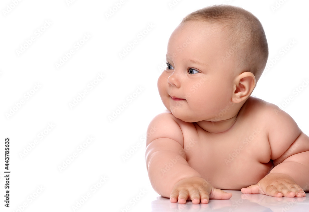 Focused infant child baby girl kid in diaper is lying on her stomach and watches aside attentively isolated on a white background Focused infant child baby girl kid in diaper is lying on her stomach and watches aside attentively isolated on a white background