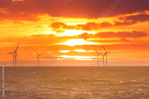 Renewable green electricity wind power generation offshore. Sunrise at decarbonization industry windmills business for regenerative energies. Clean energy renewables preventing climate change
