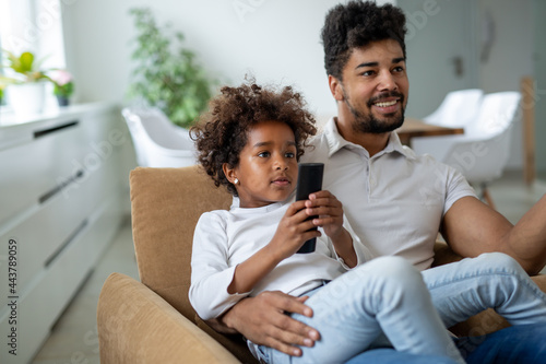 Family, fatherhood love people concept. Happy father and daughter watching tv at home