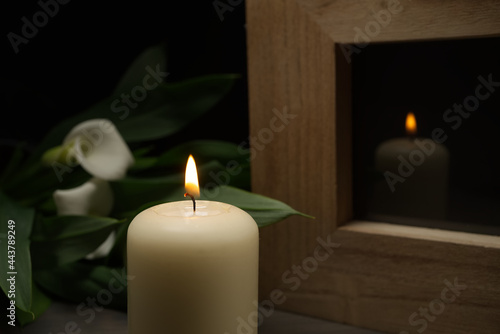 Large white candle burning in the darkness with reflection