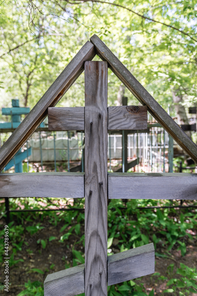 An old wooden cross stands on an abandoned grave in the cemetery. Weathered wood texture and pattern. An old wooden cross stands on an abandoned grave in the cemetery. Weathered wood texture and pattern.