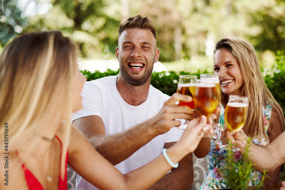Group of happy friends toasting with beer at the summer bar Group of happy friends toasting with beer at the summer bar